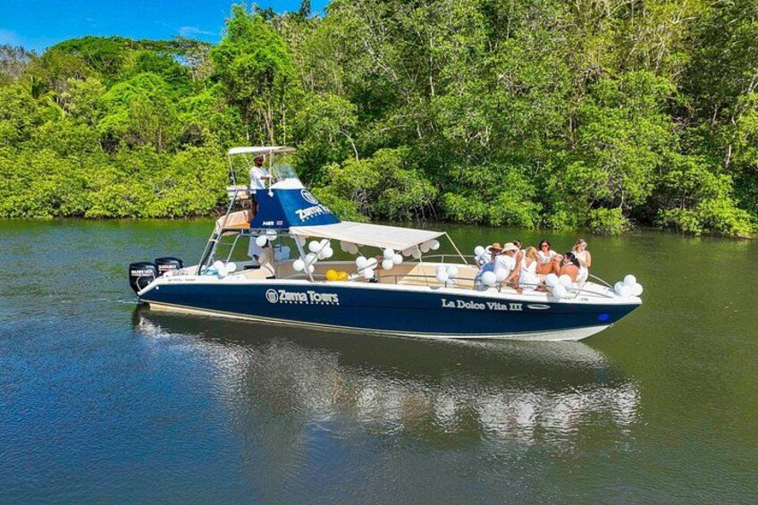 A boat named 'La Dolce Vita III' with passengers, surrounded by lush greenery. 4