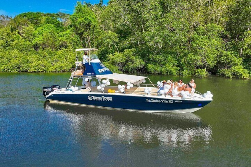 A boat named "La Dolce Vita III" with passengers, surrounded by lush greenery. 5