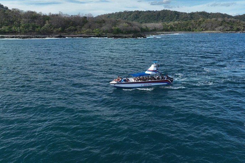 A boat on a body of water with a forested shoreline in the background. 3