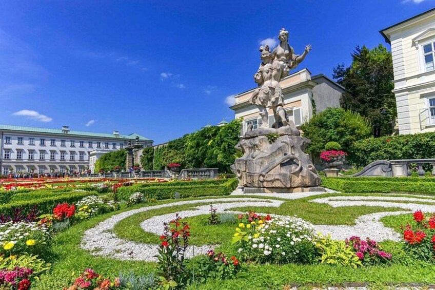 A garden with a central statue, a fountain, and a building in the background. 5