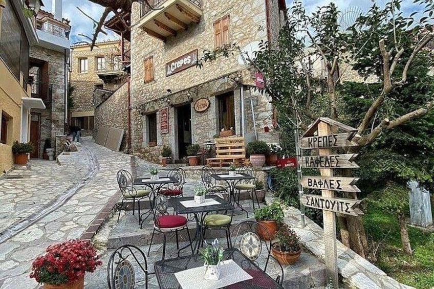 A stone-paved street with outdoor seating, a café, and directional signs. 5