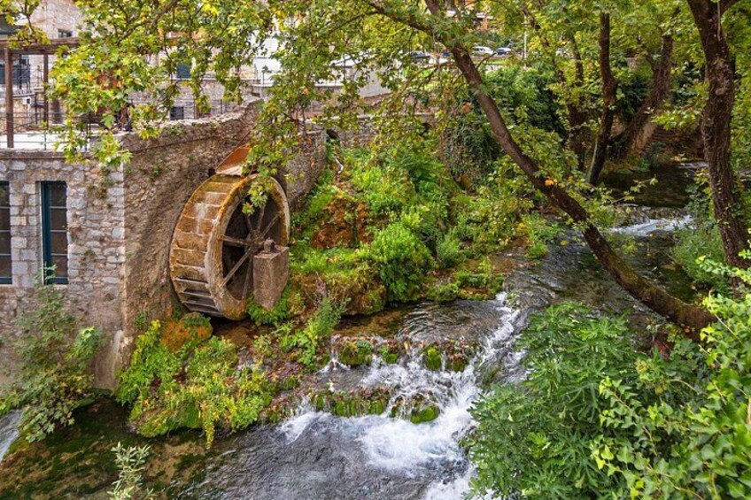 A stone water wheel, a small stream, and lush greenery. 1