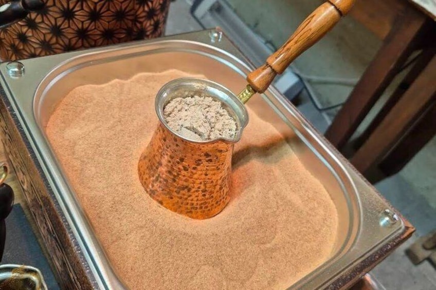 A traditional coffee brewing device with a wooden handle and a glass container filled with coffee grounds. 2