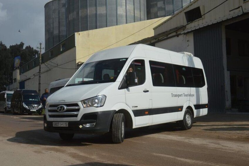 A white van with 'Transport Touristique' written on the side parked on a street. 1