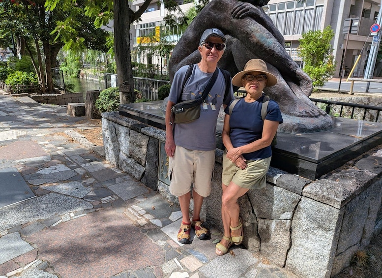 A couple posing in front of a stone sculpture of a hand. 3