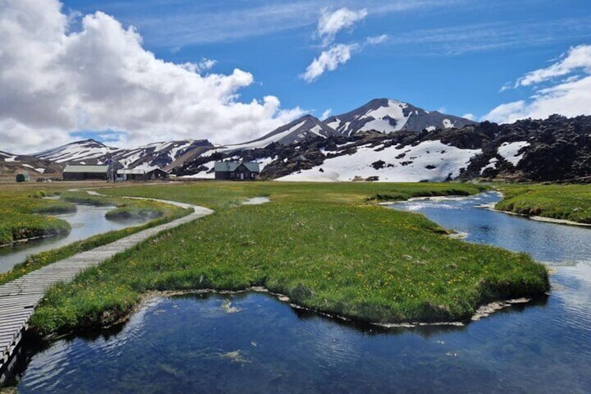 Een rivier die door een begraasd landschap slinger, met besneeuwde bergen op de achtergrond. 1