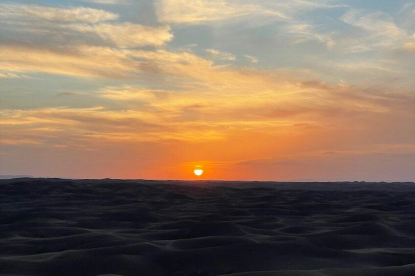 A sunset over a desert landscape with sand dunes. 4