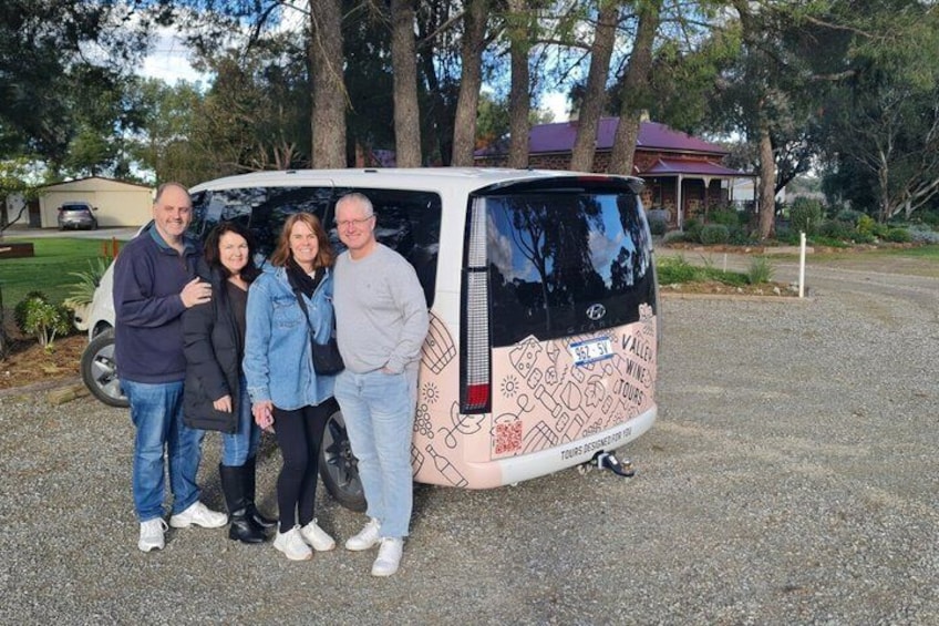 A group of people standing in front of a van with a map design on the back. 1