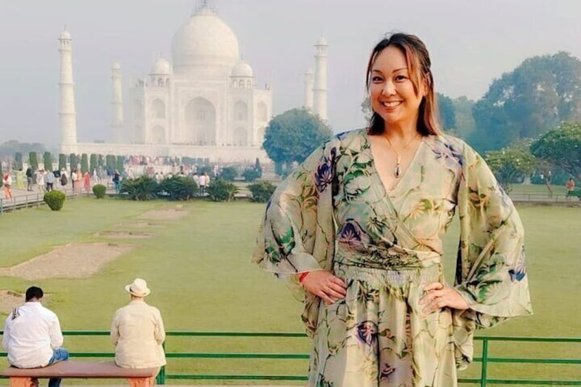 Een persoon staat voor de Taj Mahal, met een groen gazon en een wit gebouw op de achtergrond. 3