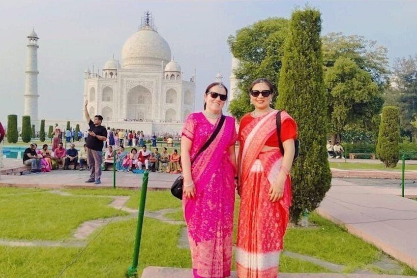 Twee mensen in traditionele kledij staan voor de Taj Mahal. 2