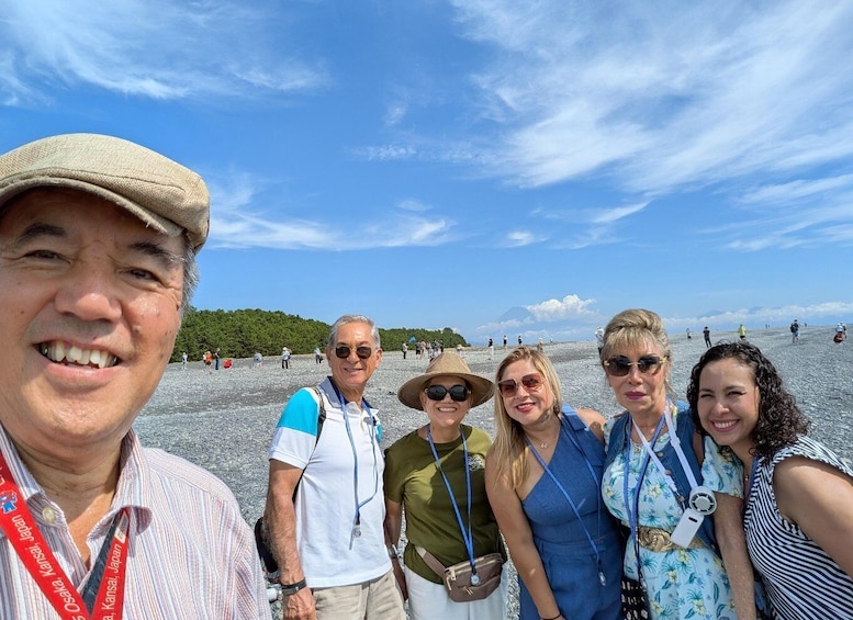 A group of people at a beach with a clear sky and distant mountains. 2
