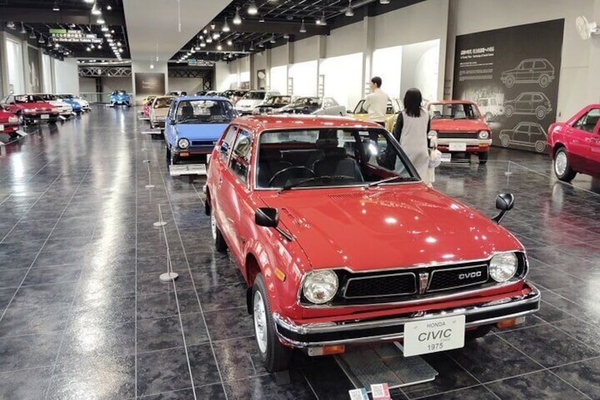 A red Honda Civic from 1975 on display in a car show with other vintage cars. 5