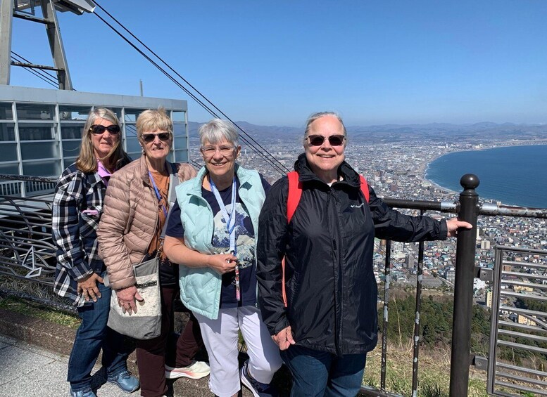 A group of people standing on a viewing platform with a cityscape and coastline in the background. 2