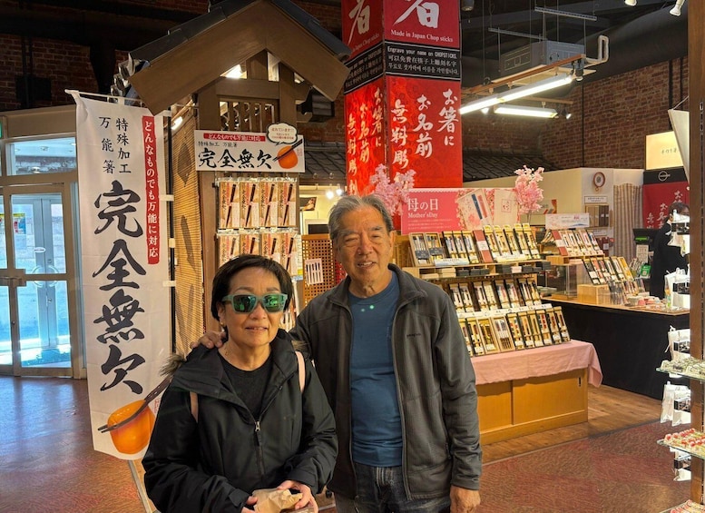 A couple standing in front of a shop with Japanese signage, surrounded by various products and decorations. 5