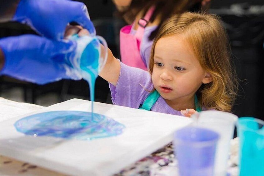 A child engaged in a painting activity with blue paint on paper. 2