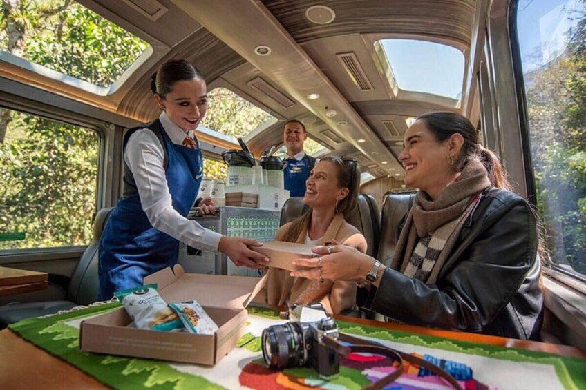 Interior de un tren con pasajeros, un camarero y una caja de aperitivos. 1