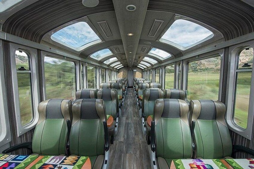 Interior de un tren con filas de asientos, ventanas amplias y suelo de madera. 5