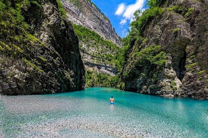 Una persona nada en un río turquesa rodeado de riscos y vegetación. 3
