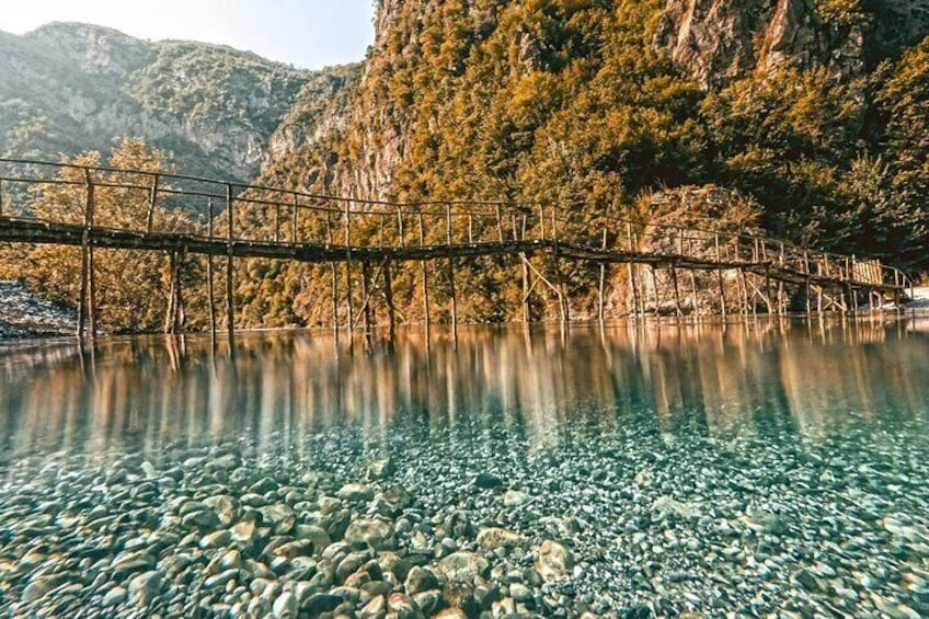 Un lago tranquilo con un puente de madera y una orilla rocosa. 4