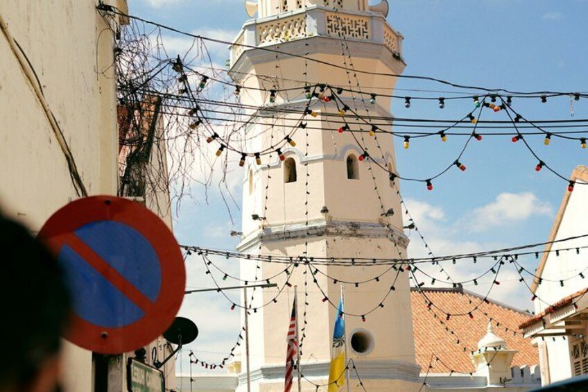 A tower with a clock, surrounded by buildings and string lights. 5