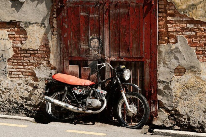 A motorcycle parked against a weathered brick wall with a red door. 1