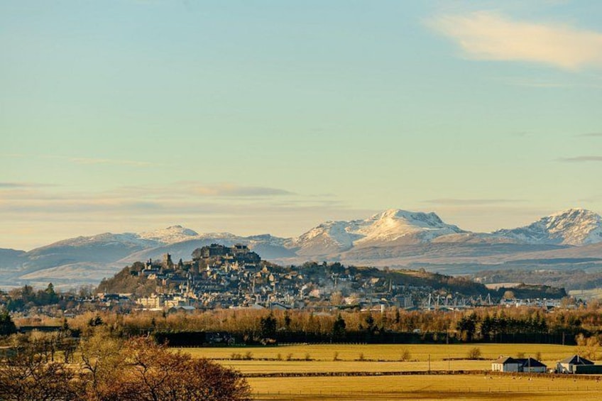 Eine Stadt liegt eingebettet in einem Tal, im Hintergrund schneebedeckte Berge. 4