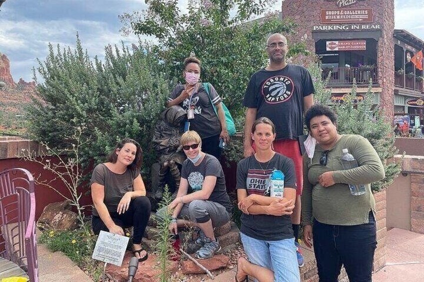 Un grupo de personas posando frente a un edificio con un letrero que dice 'Parking in Rear'. 1