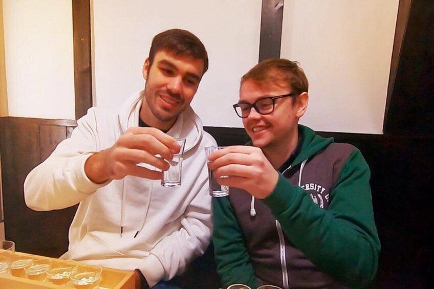 Two people sitting at a table with glasses of a clear liquid, possibly water or a beverage. 5
