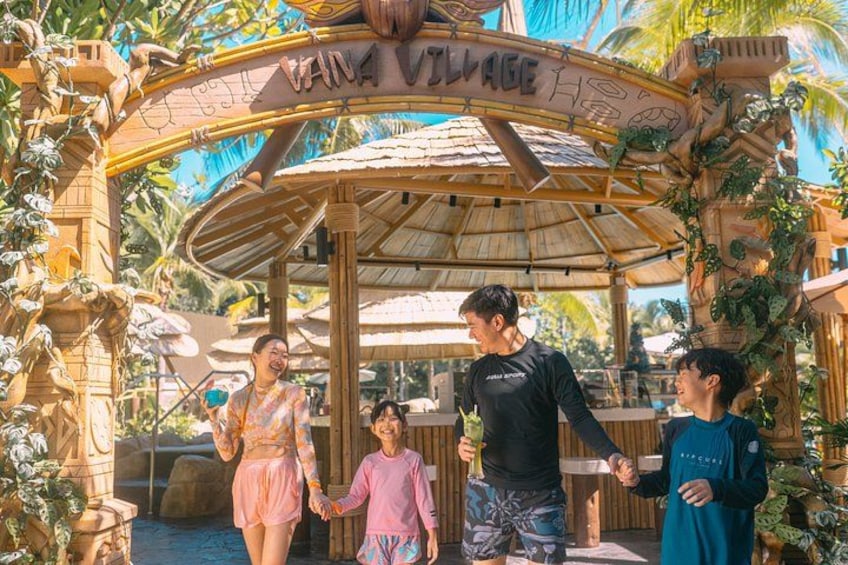 A family at a park entrance with a sign reading 'VAN! Village.' 3