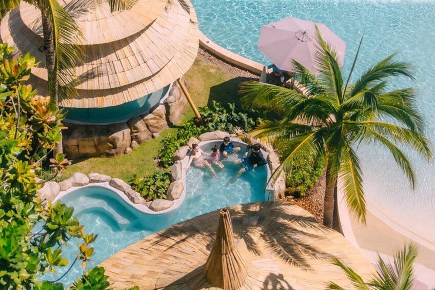 A tropical resort with a swimming pool, palm trees, and a beach. 4
