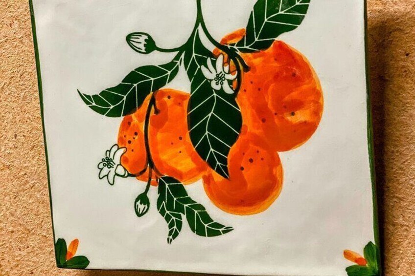 Ein Keramikteller mit einem orangefarbenen Obstgemälde. 2
