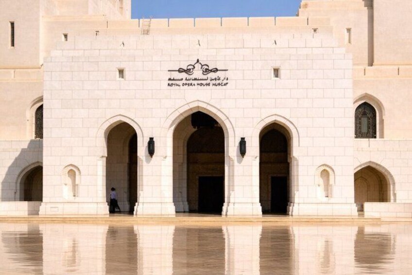 A large, ornate building with arched entrances and a reflective water surface in front. 4
