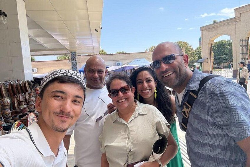 A group of people posing for a selfie in a public square with a historical monument in the background. 2