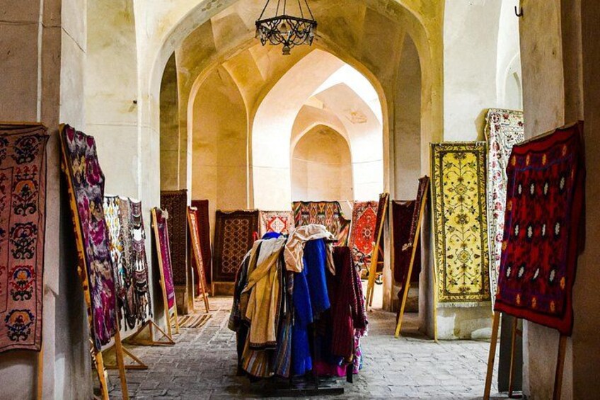 An interior with arched ceilings and a carpeted floor, displaying various textiles on easels. 4