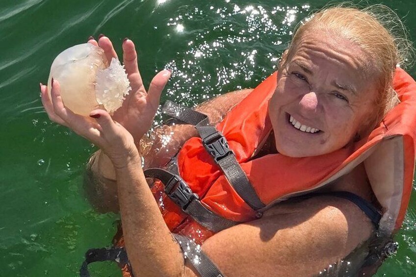 Eine Person mit Schwimmweste hält ein klares Objekt mit weißem Inneren. 5