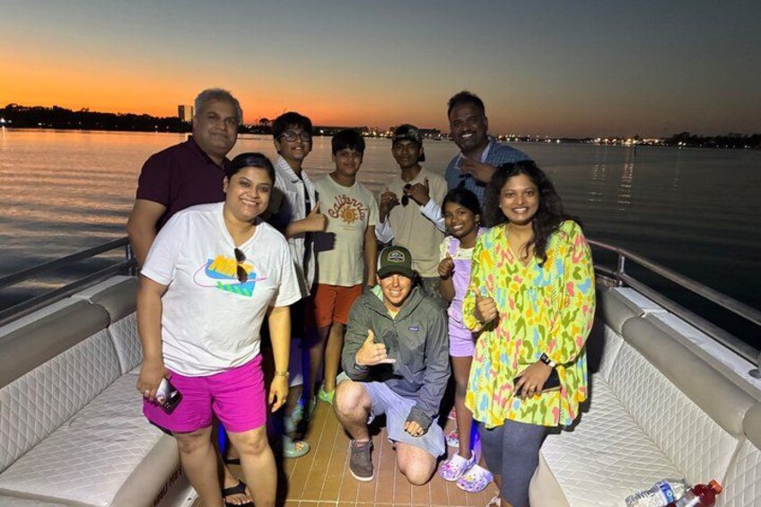 Eine Gruppe von Menschen auf einem Boot vor einem Sonnenuntergang. 2