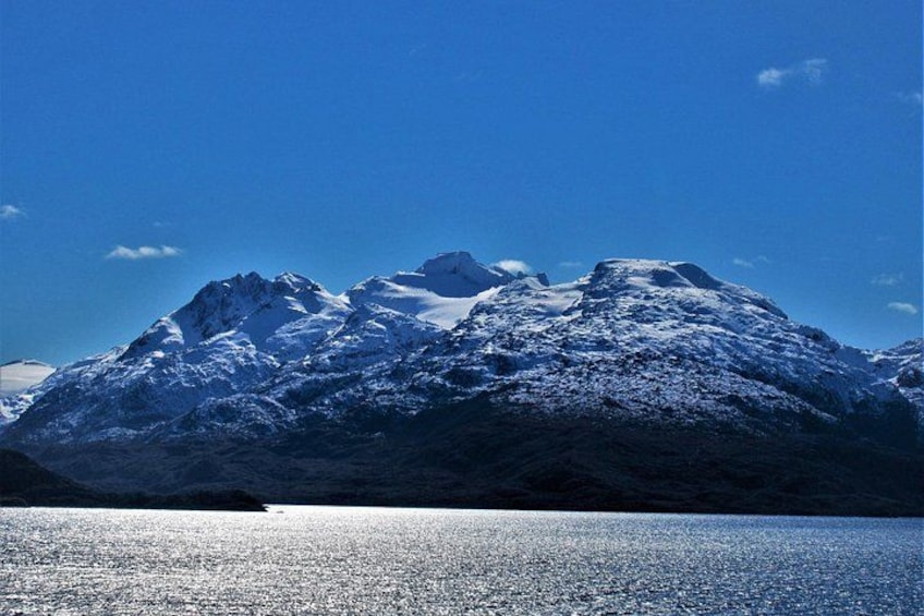 A snow-covered mountain range with a calm lake in the foreground. 1
