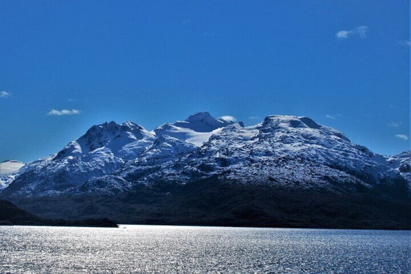 A snow-covered mountain range with a lake in the foreground. 1