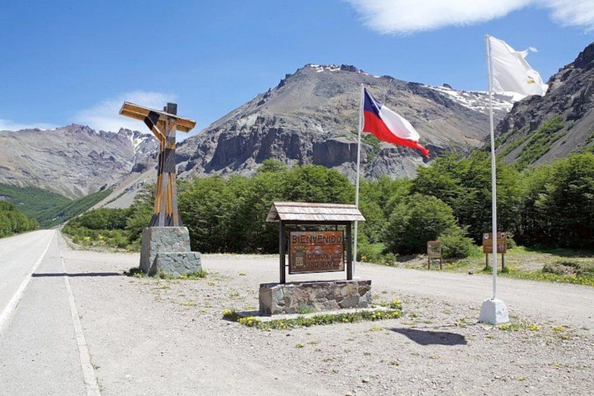 A road with a wooden cross, a sign, and two flags. 2