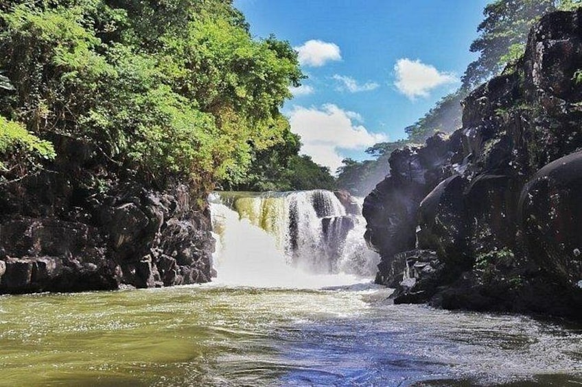 A waterfall surrounded by lush greenery and rocky terrain. 3