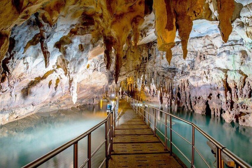 A cave with a wooden walkway and a pool of water. 1