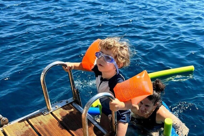 Two people on a boat in the water, holding orange life jackets. 5