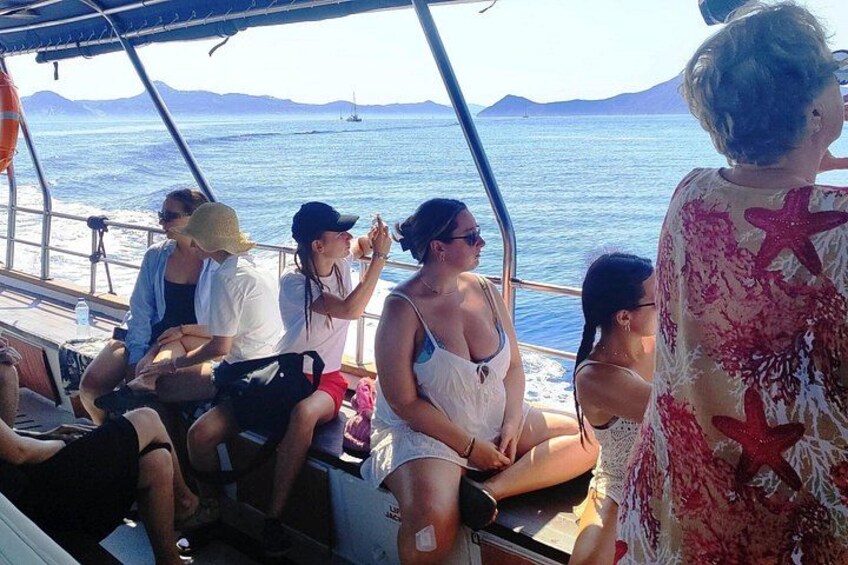 A group of people on a boat with a clear view of the ocean and distant mountains. 4