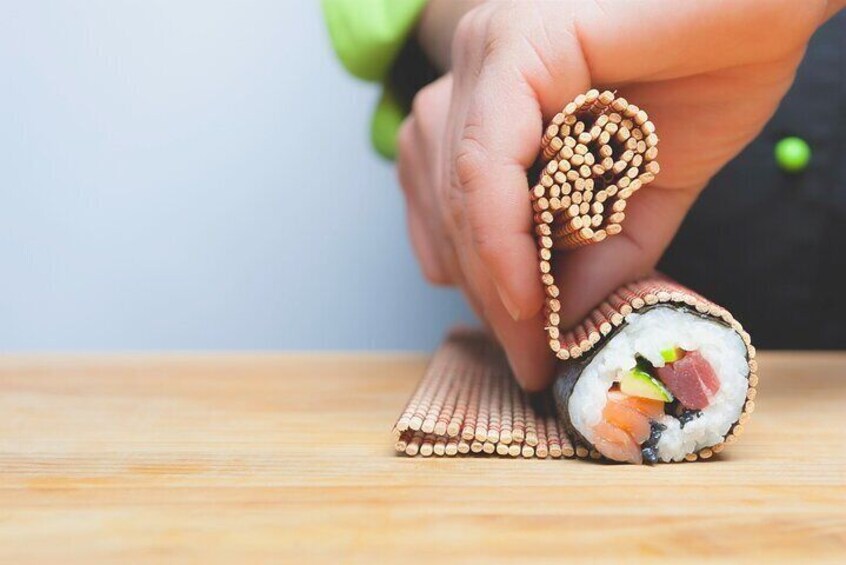 Una mano sostiene un rollo de sushi con ingredientes visibles como pescado, aguacate y pepino. 1