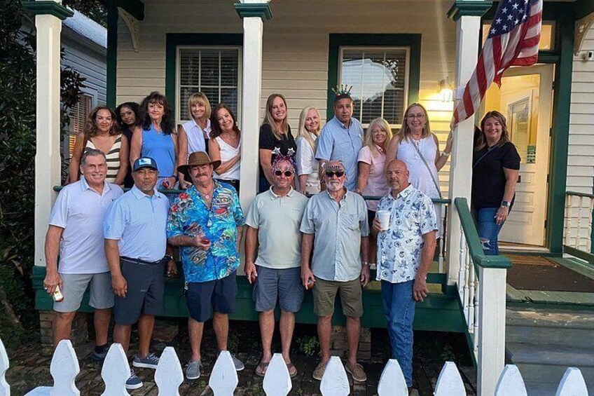 A group of people standing on a porch with an American flag. 1