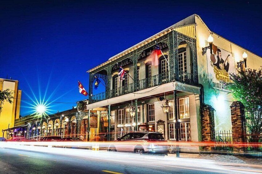 A historic building with a marquee sign, flags, and a street view at night. 3