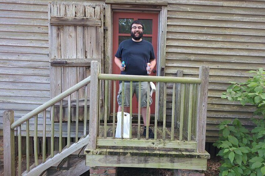 A wooden house with a red door, a wooden staircase, and a metal railing. 2