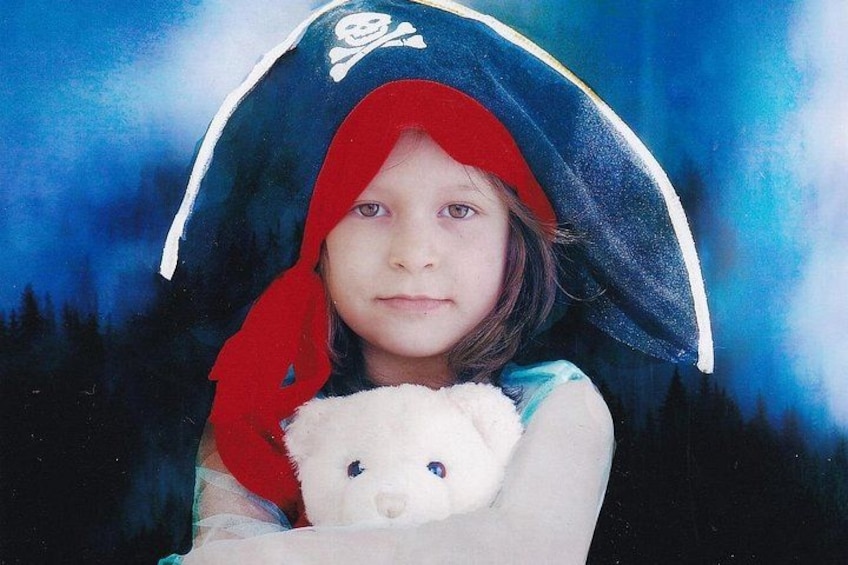 A person holding a teddy bear, wearing a pirate hat with a skull and crossbones emblem. 3