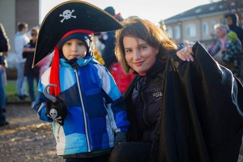 A person in a pirate costume with a black hat and a skull emblem, holding a black bag. 1