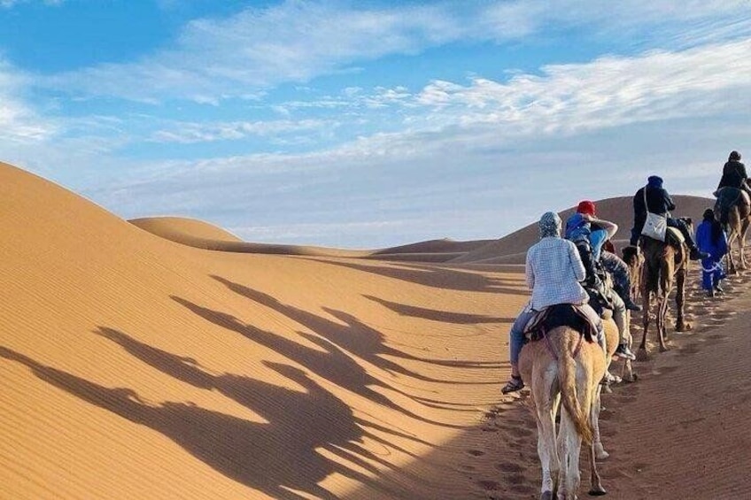 A group of people riding camels through a desert landscape with sand dunes. 5